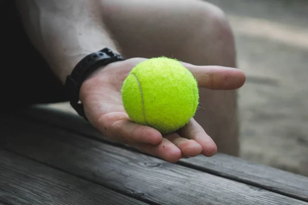 Hombre sosteniendo una pelota de tenis verde en la calle — Foto de Stock