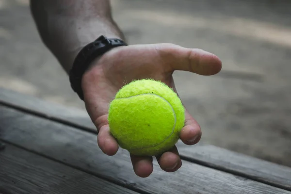 Hombre sosteniendo una pelota de tenis verde en la calle — Foto de Stock