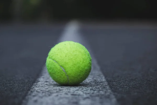 Pelota de tenis verde acostado en el camino a lo largo del centro en una tira blanca — Foto de Stock