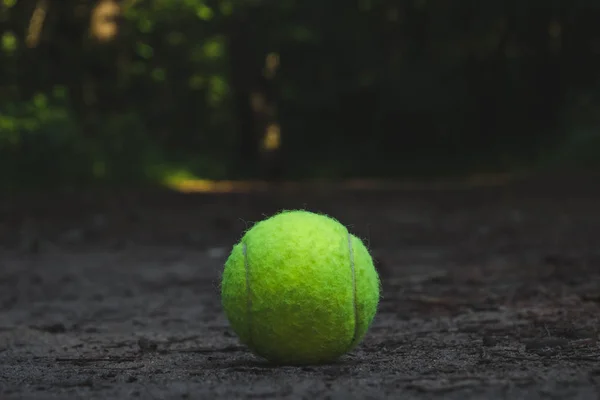 Balle de tennis verte couchée sur le sol — Photo