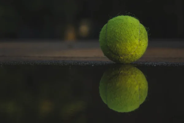 La pelota de tenis está cerca del charco, la pelota se refleja en el agua — Foto de Stock
