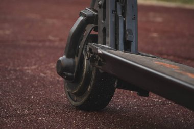 siyah elektrikli scooter parkta kauçuk ped üzerinde duran, ön arka.