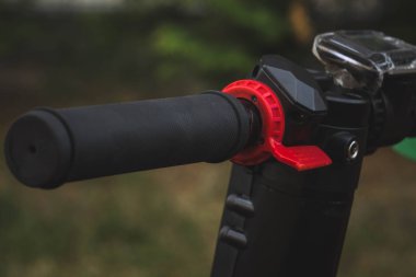 siyah elektrikli scooter parkta lastik ped üzerinde duran, direksiyon görünümü.