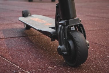 siyah elektrikli scooter parkta kauçuk ped üzerinde duran, ön arka.