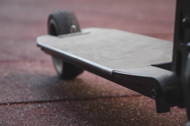 siyah elektrikli scooter parkta kauçuk ped üzerinde duran, ön arka.