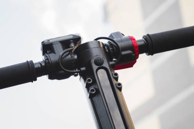 siyah elektrikli scooter parkta lastik ped üzerinde duran, direksiyon görünümü.