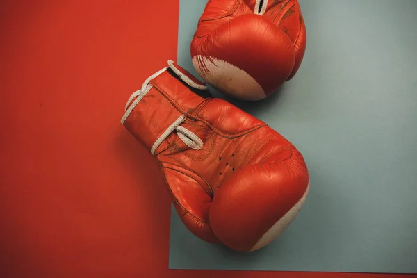 Rode bokshandschoenen op een rode en blauwe achtergrond. — Stockfoto