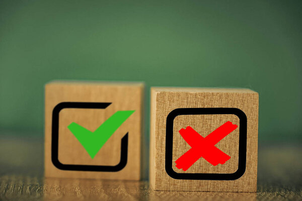 wooden cubes with the image of check marks marks on a green background.