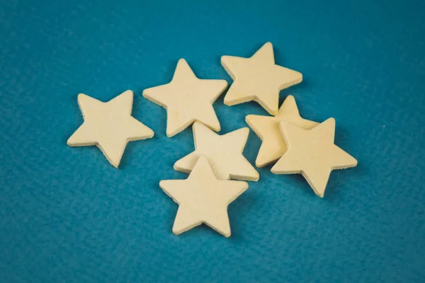 Ένα μάτσο ξύλινα αστέρια σε ένα μπλε φόντο χαοτικά διασκορπισμένα. — Φωτογραφία Αρχείου