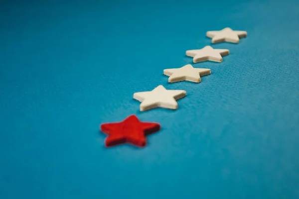 Un mazzo di stelle di legno e una di esse è evidenziata in rosso. soggetto su sfondo blu — Foto Stock