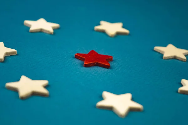 Ένα μάτσο ξύλινα αστέρια και ένα από αυτά επισημαίνεται με κόκκινο χρώμα. θέμα σε μπλε φόντο. — Φωτογραφία Αρχείου