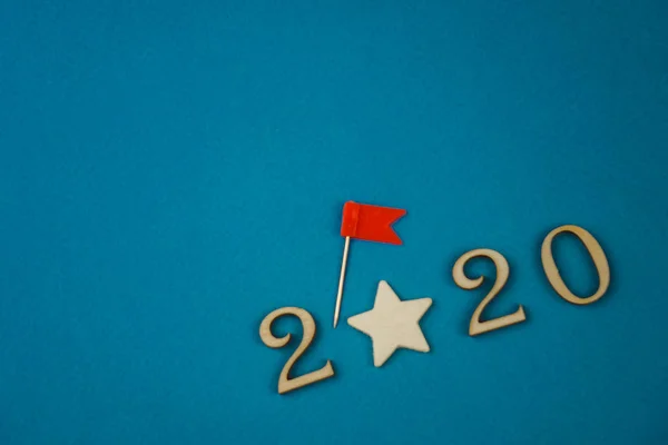 2020-Zahl aus Holzzahlen auf blauem Hintergrund mit verstreuten Sternen und Flaggen — Stockfoto