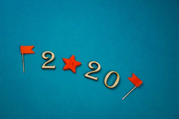 2020 αριθμός από ξύλινους αριθμούς σε μπλε φόντο με διάσπαρτα γρανάζια αστεριών και σημαίες γύρω από — Φωτογραφία Αρχείου