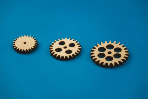 Wooden gear on a blue background. Abstract background for presentations and banners. The concept of technology and industry, the think process. Part of a large complex mechanism. Banner.