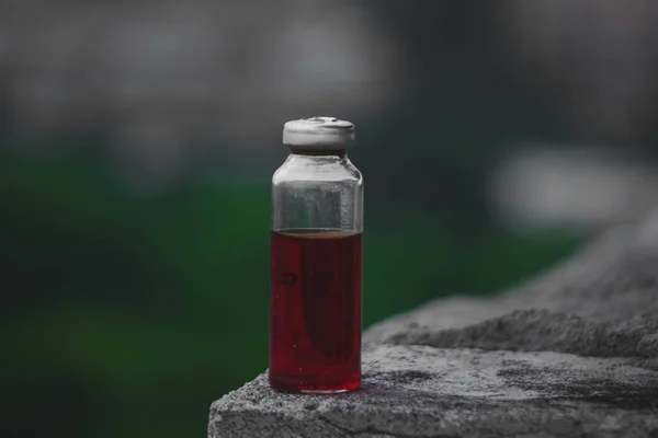 Taş yüzey üzerinde duran kırmızı çözeltili Erlenmeyer şişesi. — Stok fotoğraf