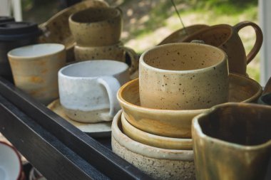 ahşap bir rafta renkli seramik kupalar