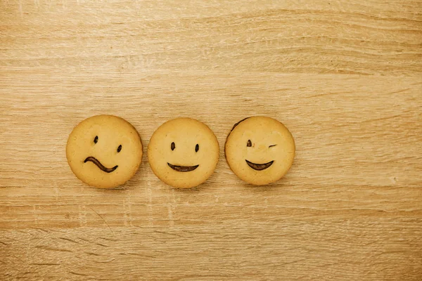 Usmívající se sušenky a různé emoce na dřevěném pozadí. — Stock fotografie