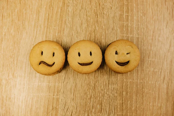 Uśmiechnięte ciasteczka i różne emocje na tle drewna. — Zdjęcie stockowe
