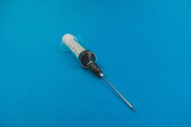 mavi bir arka plan üzerinde yatan bir iğne ile tıbbi şırınga