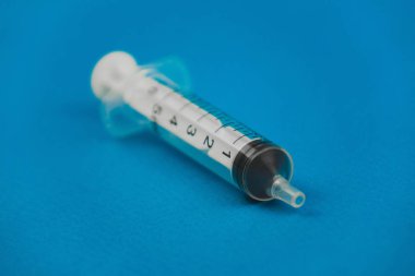 mavi bir arka plan üzerinde yatan tıbbi şırınga