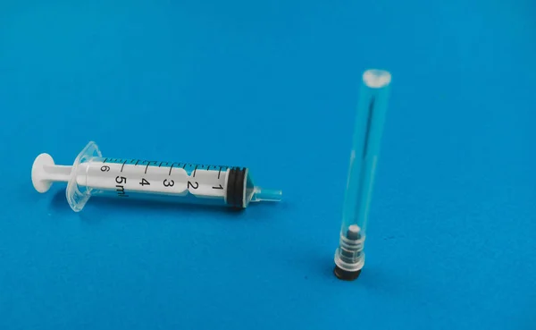 Medische spuit met een naald liggend op een blauwe achtergrond — Stockfoto