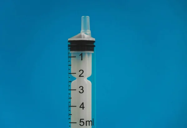 Medical syringe lying on a blue background — Stock Photo, Image