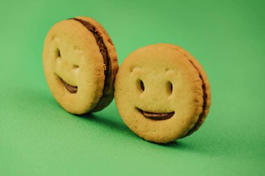 yeşil bir arka plan üzerinde gülümseyen çerezler ve farklı duygular