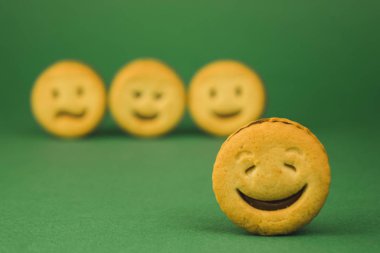 yeşil bir arka plan üzerinde gülümseyen çerezler ve farklı duygular