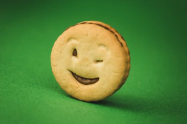 yeşil bir arka plan üzerinde gülümseyen çerezler ve farklı duygular