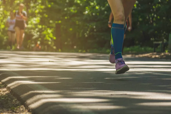 Female runner jogging down an outdoor trail at sunset in sneakers.