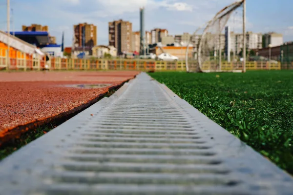 Pista de jogging con rejilla de metal y hierba verde . — Foto de Stock