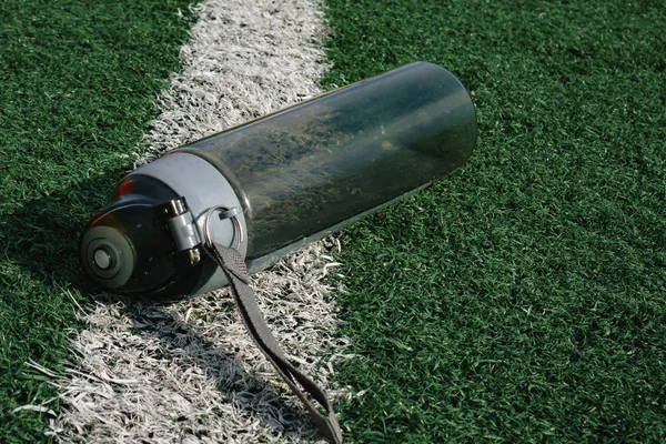 Plastic fles water liggend op gras voetbalveld. — Stockfoto