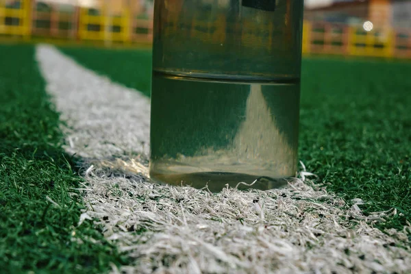Garrafa de plástico de água deitada no campo de futebol grama . — Fotografia de Stock