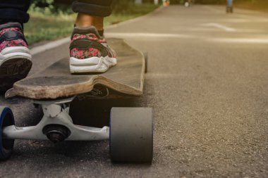 Atlet ayağı ile Longboard dağlarda yolda. Güneş ışığı.