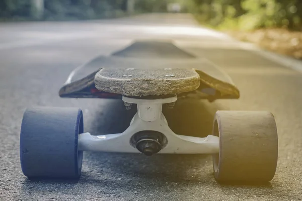 Longboard standing on the asphalt in the forest close seup — стоковое фото