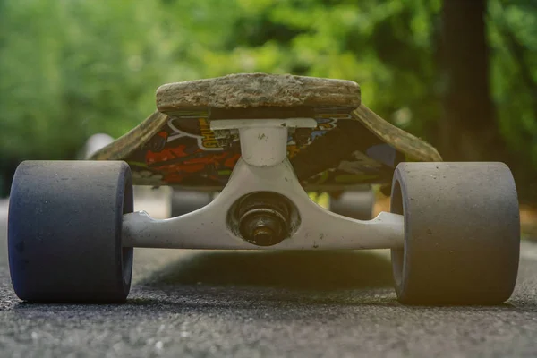 Longboard standing on the asphalt in the forest closeup — Stock Photo, Image