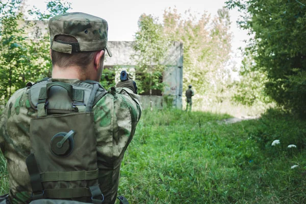 Militair in de vorm van het richten en proberen om een pistool te schieten. Achteraanzicht — Stockfoto