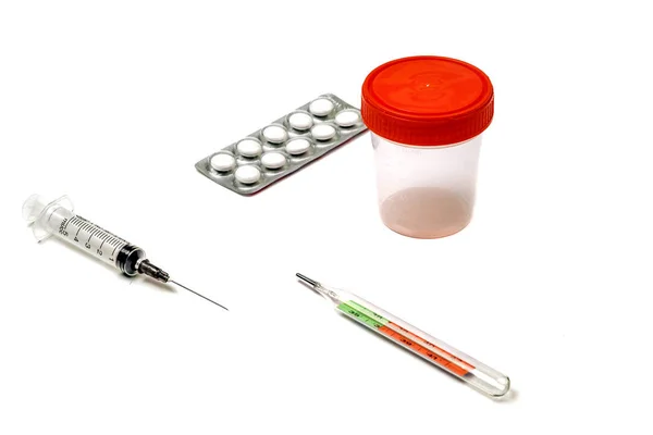 Tablettákat, fecskendőt, hőmérőt és orvosi tárgyakat fehér alapon. — Stock Fotó
