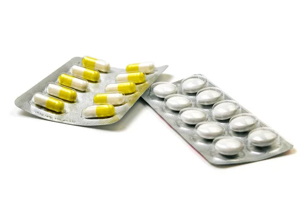 Comprimidos amarillos y blancos en un envase aislado sobre un fondo blanco — Foto de Stock
