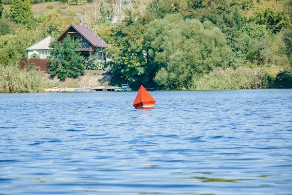 White cottage house on the other side of the river. Sunny day. A red buoy floats on the water — Stock Photo, Image