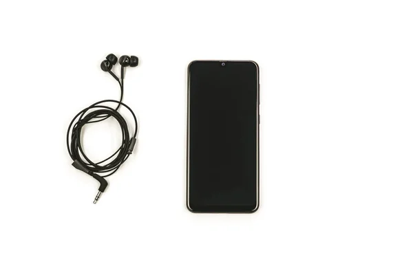Auriculares negros y teléfono inteligente sobre fondo blanco . —  Fotos de Stock