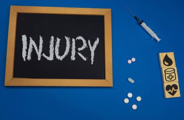 kelime Yaralanma ile mavi tıbbi masa üzerinde ahşap tablet