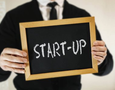 kravat ile takım elbise erkek işadamı elinde yazıt Start-Up ile bir işaret tutar