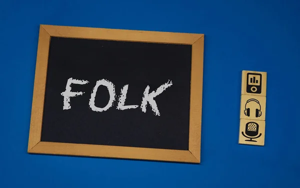 Надпись FOLK на черной доске с синим фоном с тремя деревянными кубиками — стоковое фото