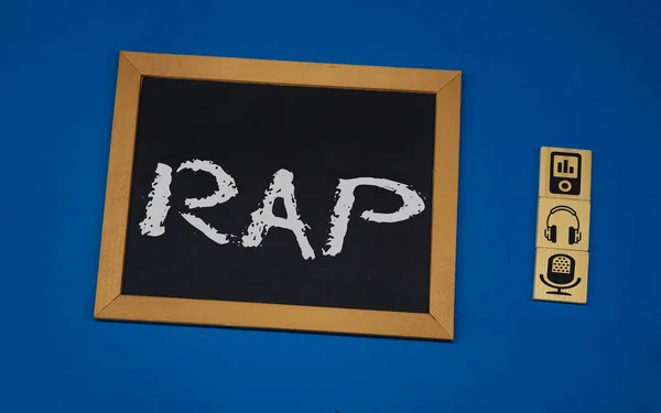 Inscripción RAP en un tablero negro con un fondo azul con tres cubos de madera —  Fotos de Stock