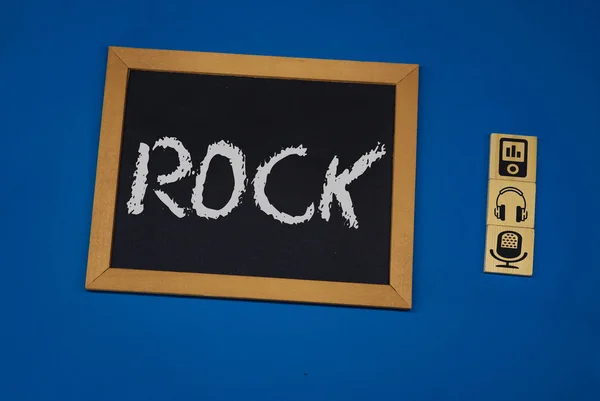 Inscripción ROCK sobre un tablero negro con un fondo azul con tres cubos de madera — Foto de Stock