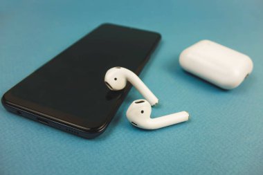 Berlin Almanya 03.11.2019. Apple kulaklıklar siyah bir telefon üzerinde yalan.