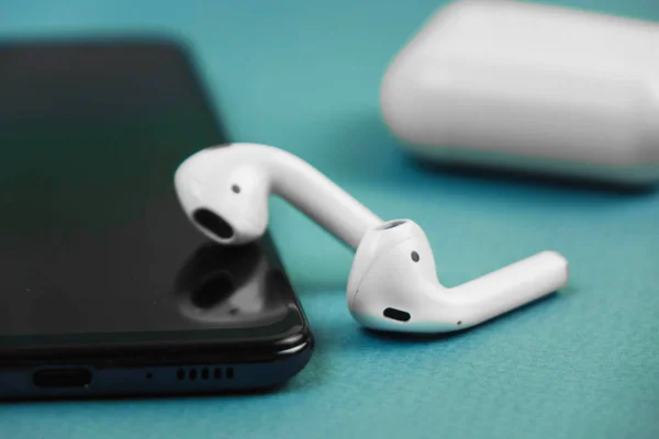 Apple headphones lying on a black phone. — Stock Photo, Image