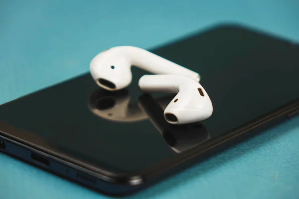 Berlín Alemania 03.11.2019. Auriculares Apple tumbados en un teléfono negro . —  Fotos de Stock