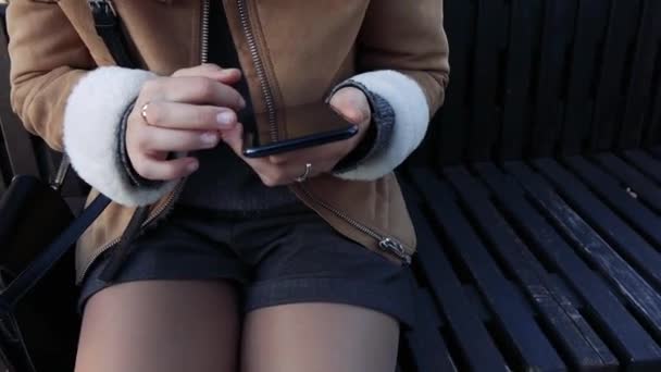 Chica sentada en un smartphone en la calle — Vídeo de stock